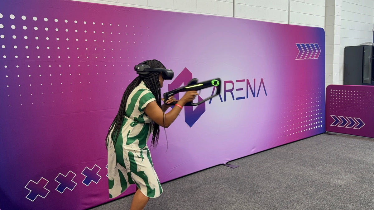 Player in a VR headset aiming a tracked rifle controller at the RealityLink wall